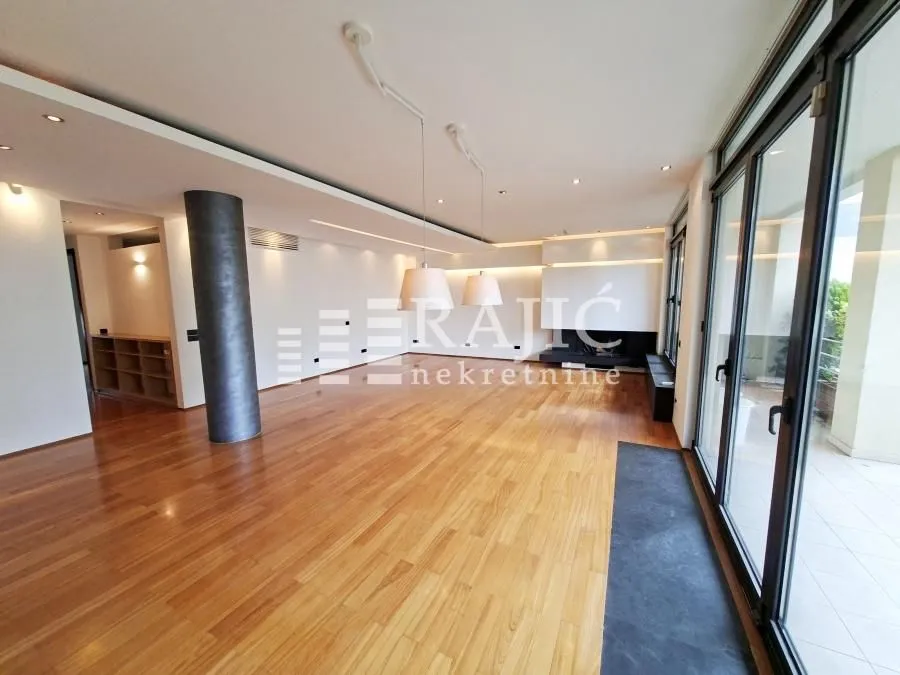 Spacious empty living room with parquet flooring and large glass doors.