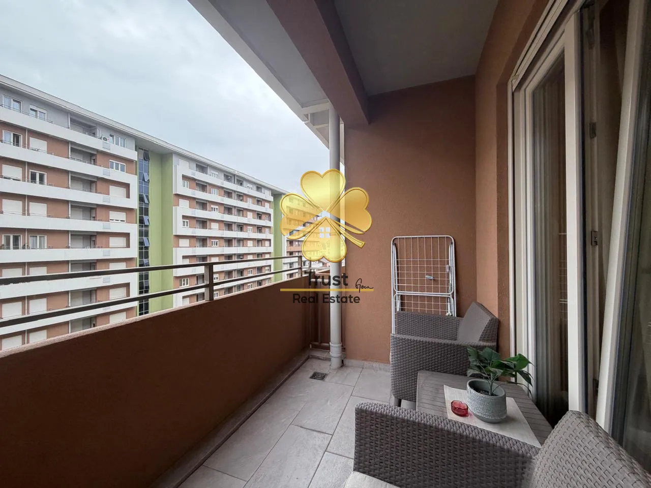 Furnished balcony with seating set and view of buildings.