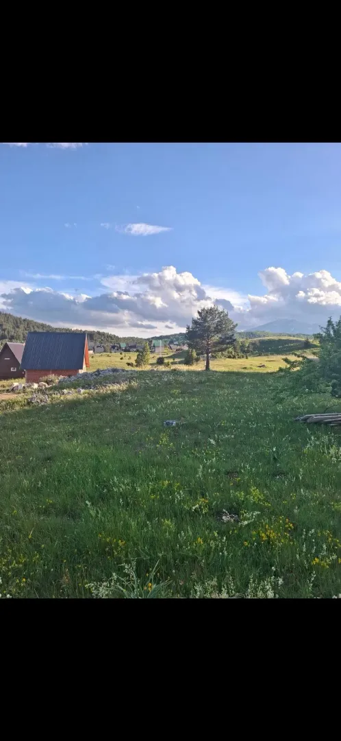 Pogled na prirodno okruženje sa vikendicom i zelenom površinom.