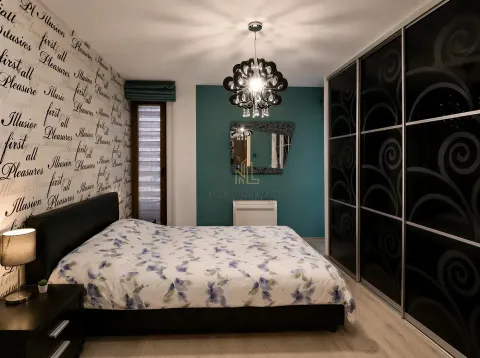Furnished bedroom with a double bed, large wardrobe, and decorative wallpaper. - image 13