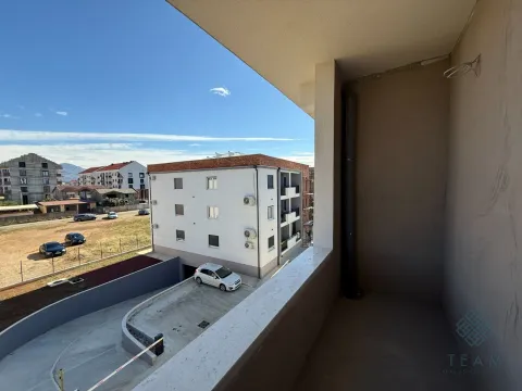 Nenamješten balkon sa pogledom na susjedne zgrade i parking. - image 2