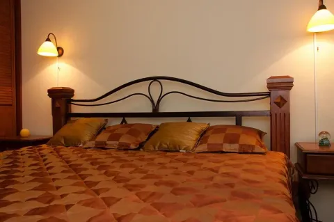 A cozy double bed with decorative pillows and bedside lamps in a bedroom. - image 5