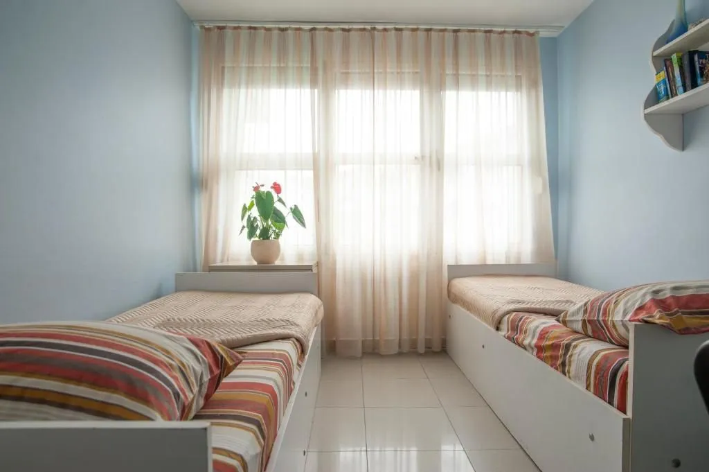 Children's bedroom with two single beds and a window with curtains.