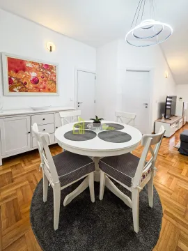 Dining area with a round table and white chairs as part of the living room. - image 4