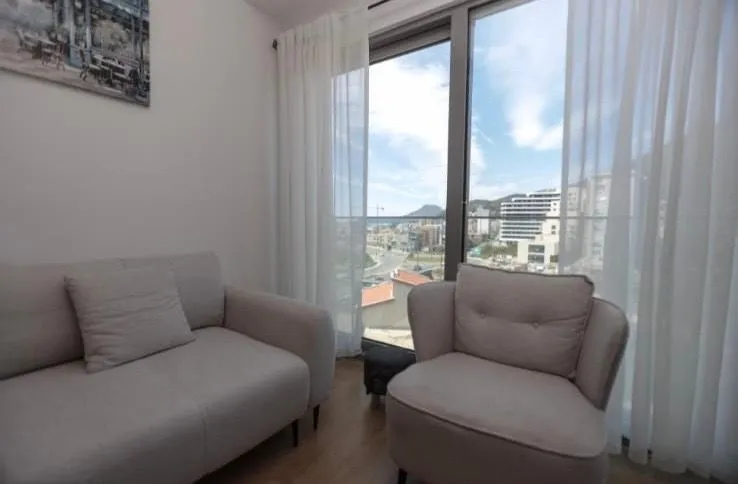 Living room with sofa set and a large window offering a city view.