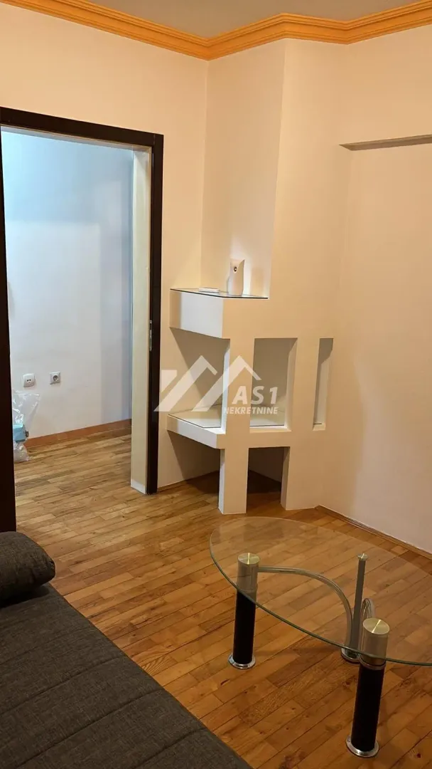 Dnevni boravak sa parketom i ukrasnim zidnim elementom.