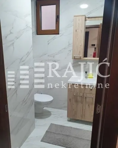 Modern bathroom with a sink, cabinet, mirror, and toilet bowl.