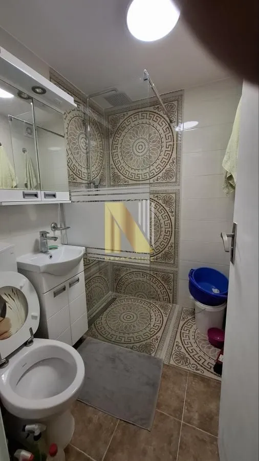 Kupatilo opremljeno sanitarijama i tuš kabinom sa dezeniranim pločicama.