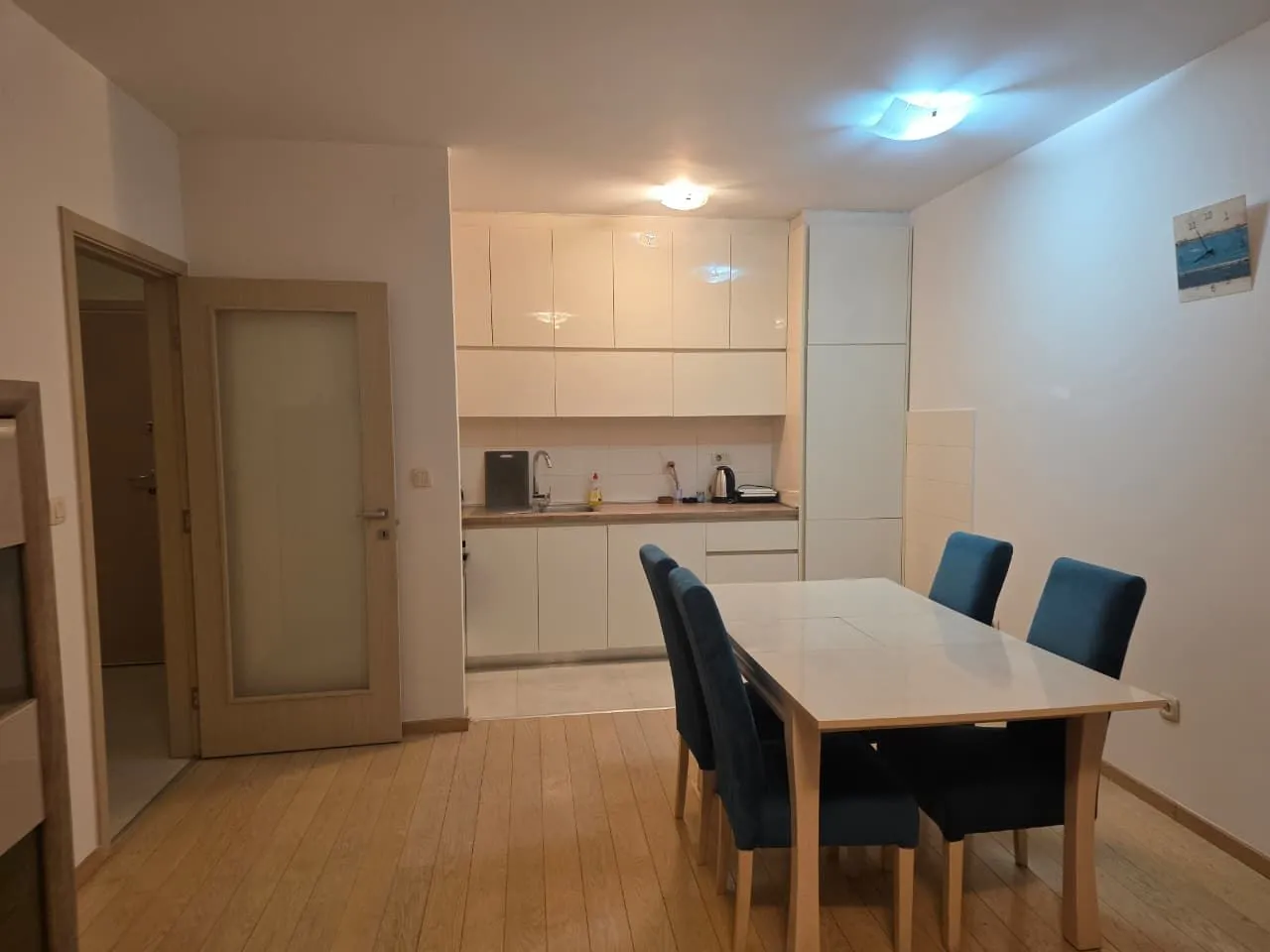 Smaller kitchen with a dining table and blue chairs.
