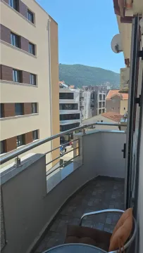 Small balcony with a metal railing and a view of buildings and a hill. - image 8