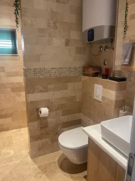 Moderno opremljeno kupatilo sa lavaboom, wc šoljom i zidnim pločicama u bež tonovima. - image 12