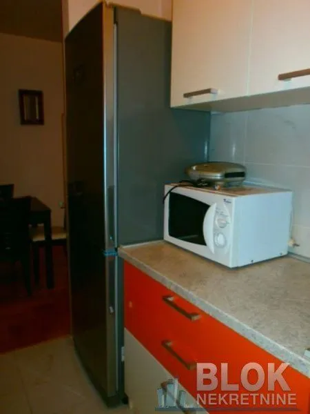 Part of the kitchen with a refrigerator, countertop, and microwave.
