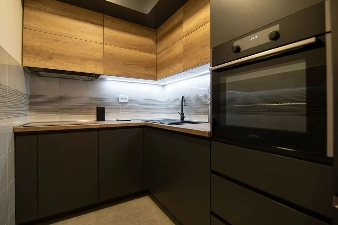 Modern kitchen with dark cabinetry and wooden details.