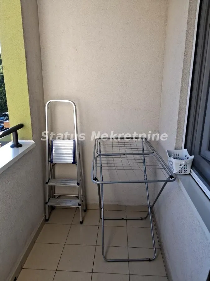Manji natkriveni balkon sa sušilicom za veš i malim merdevinama.