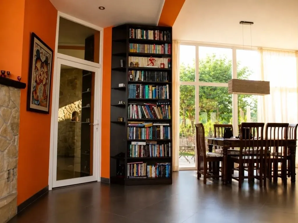 Living room with a large bookcase, dining area, and a view of the courtyard.