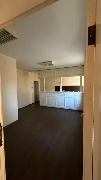 Empty room with wooden flooring and a service counter in the background. - image 4