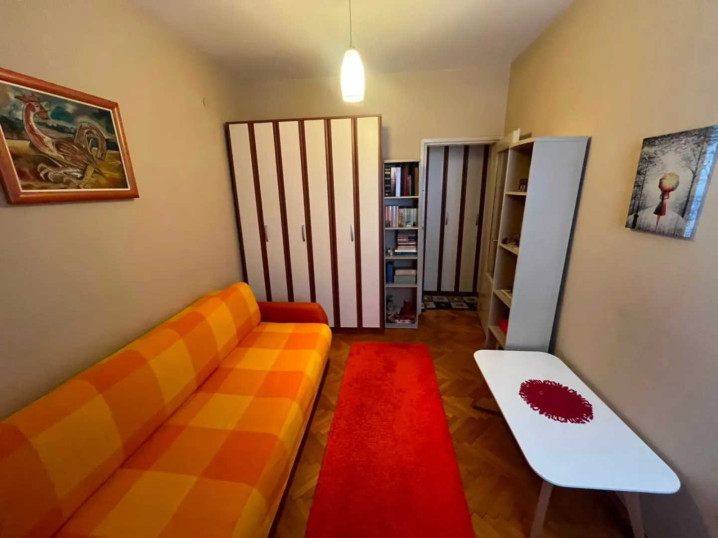 Dnevna soba sa garniturom, ormarom, policama i stočićem.