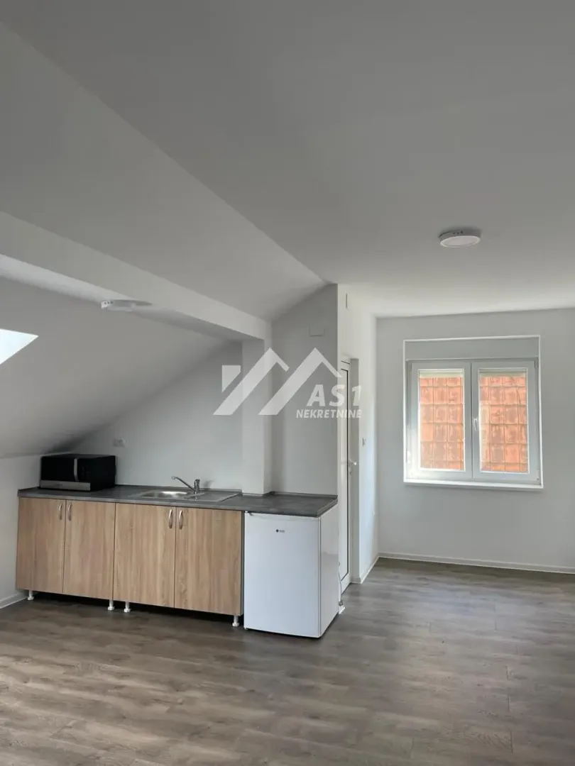 Smaller attic kitchen with a sink, base cabinets, and a refrigerator.
