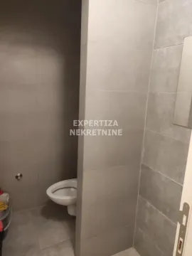View of the bathroom with grey wall tiles and a built-in toilet. - image 6