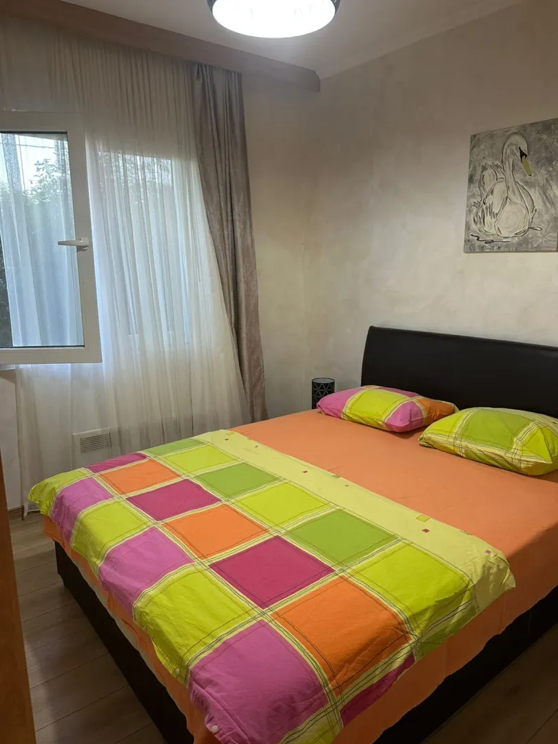 Furnished bedroom with a double bed, window, and a painting on the wall.