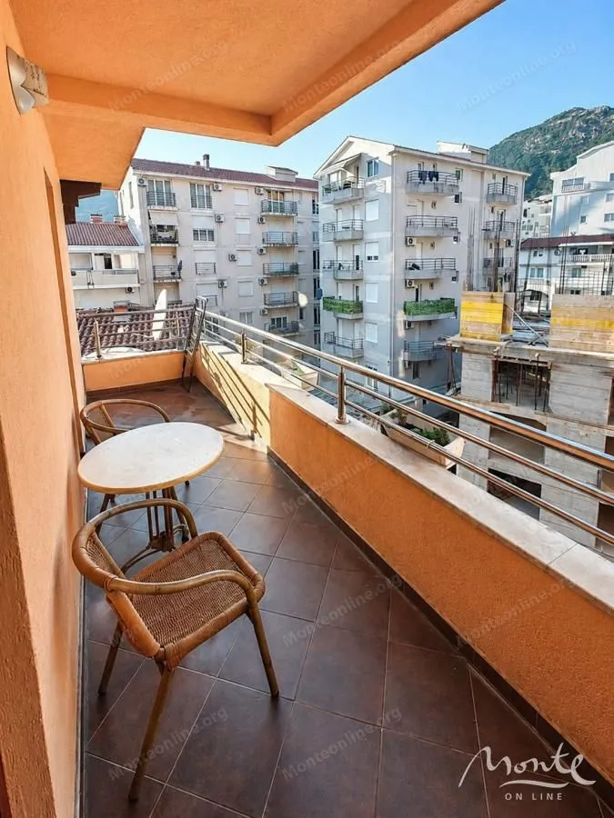 Namtješten balkon sa stolom i stolicama i pogledom na okolne zgrade.