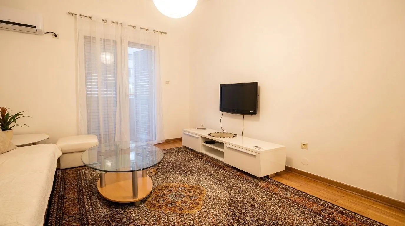 Living room with a sofa, coffee table, television, and access to the terrace.
