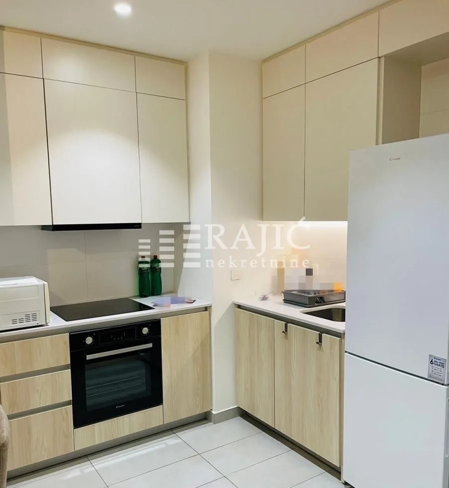 Modern kitchen with white cabinetry and built-in appliances.