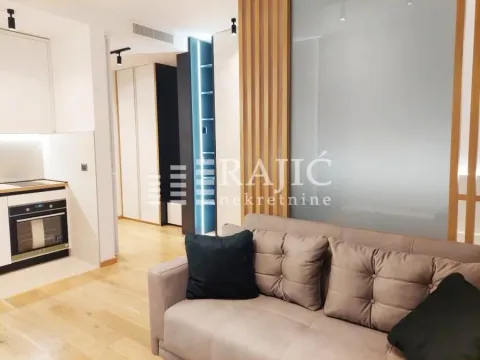 Modern living room with a sofa and a view towards the hallway and kitchen. - image 4