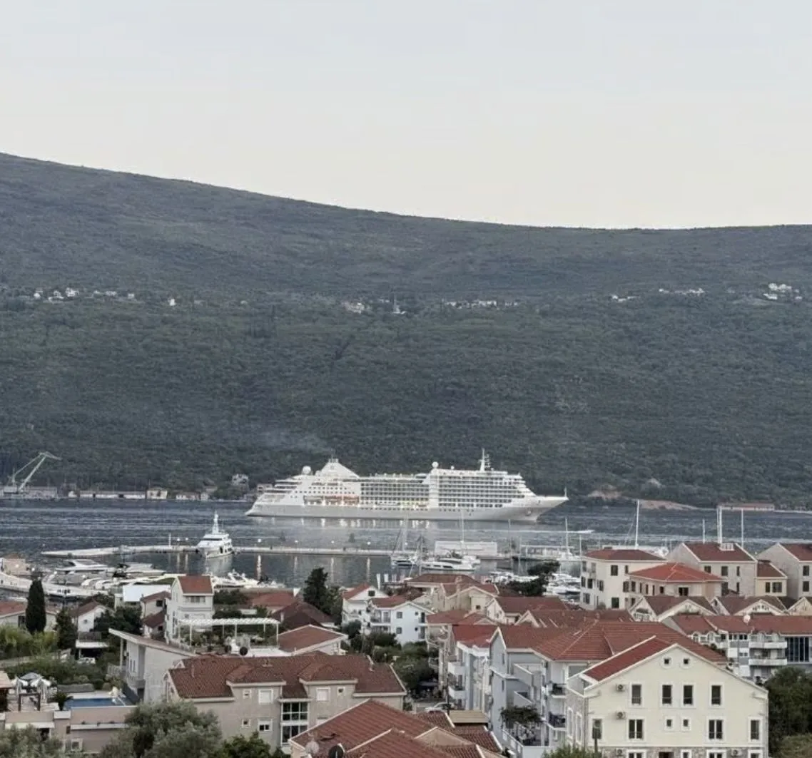 Pogled iz apartmana na grad i more sa kruzerom.