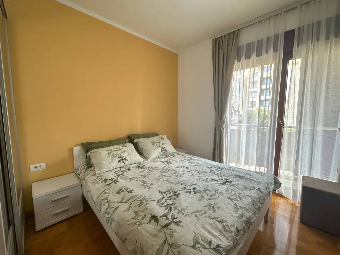 Bright bedroom with a double bed, nightstands, and a yellow accent wall.