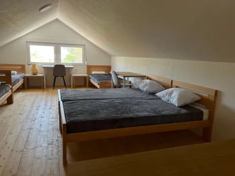 Potkrovlje opremljeno sa nekoliko drvenih kreveta i radnim stolovima. - image 18