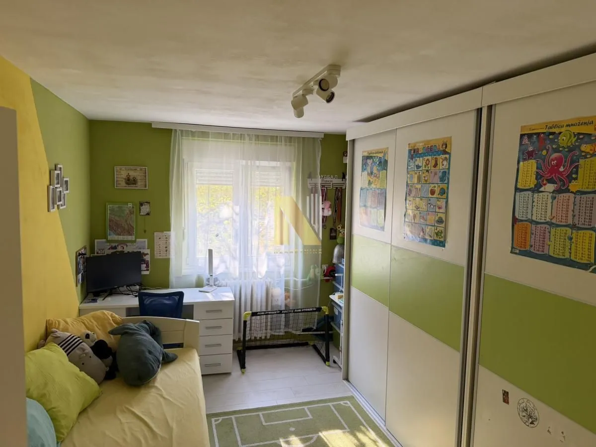 Dečja soba sa krevetom, radnim stolom i velikim plakarom.