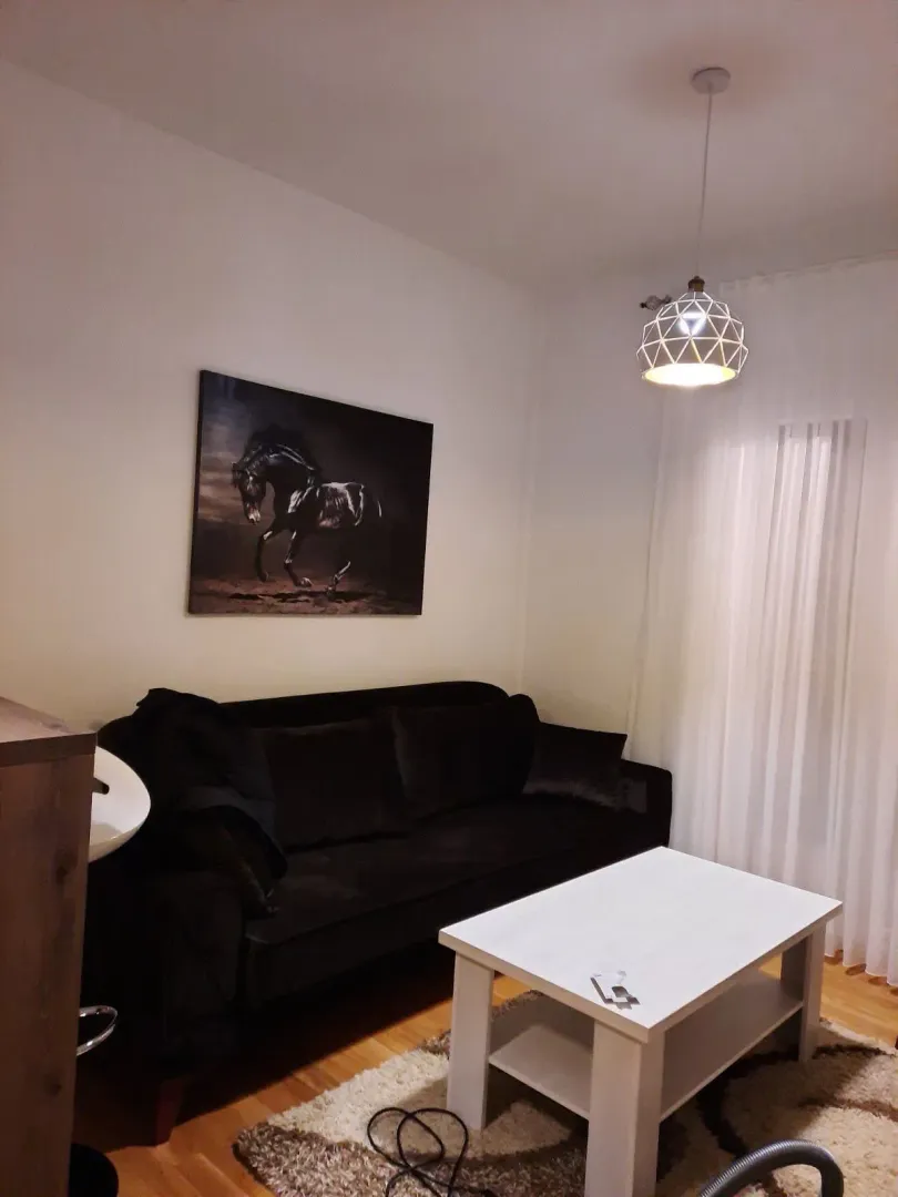 Living room with a black sofa, white coffee table and an art painting on the wall.
