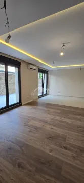 Prazna dnevna soba sa drvenim podom, spuštenim plafonom sa rasvetom i velikim staklenim vratima. - image 6