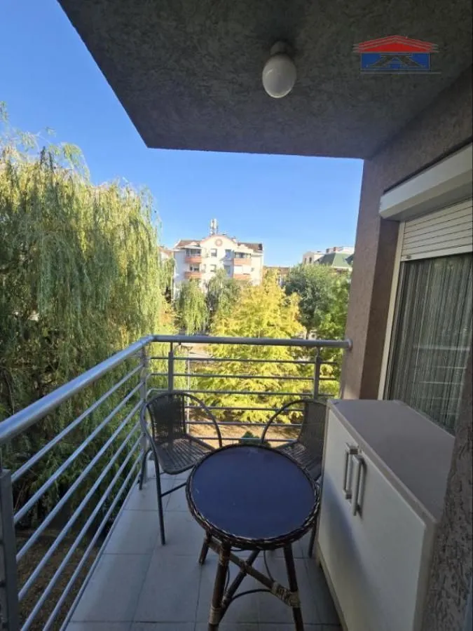Namješten balkon sa stolom, stolicama i pogledom na zelenilo.