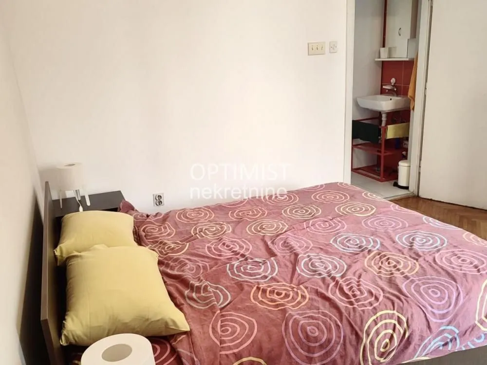 Spavaća soba sa bračnim krevetom i pogledom na kupatilo u pozadini.