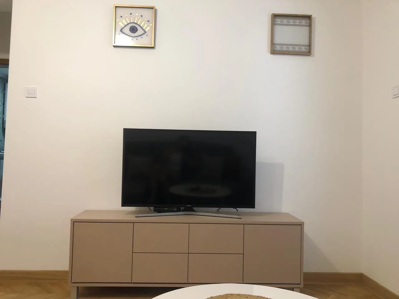 TV cabinet with a television and wall art in the living room.