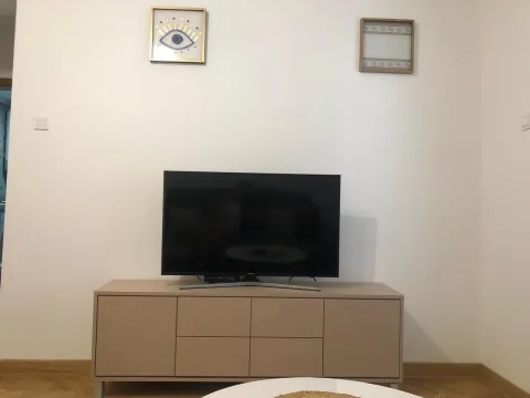 TV cabinet with a television and wall art in the living room. - image 2