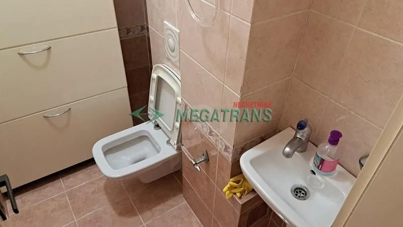 Manje kupatilo sa WC šoljom, umivaonikom i pločicama.