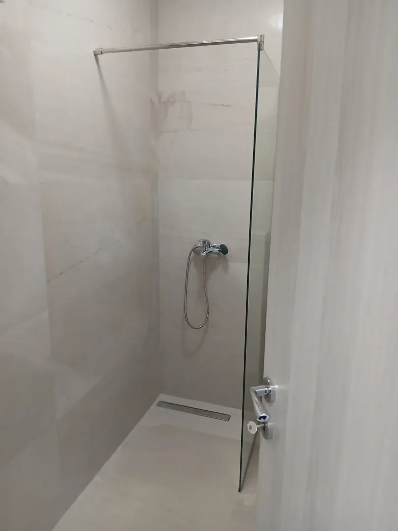 Simple shower with a glass partition in the bathroom.