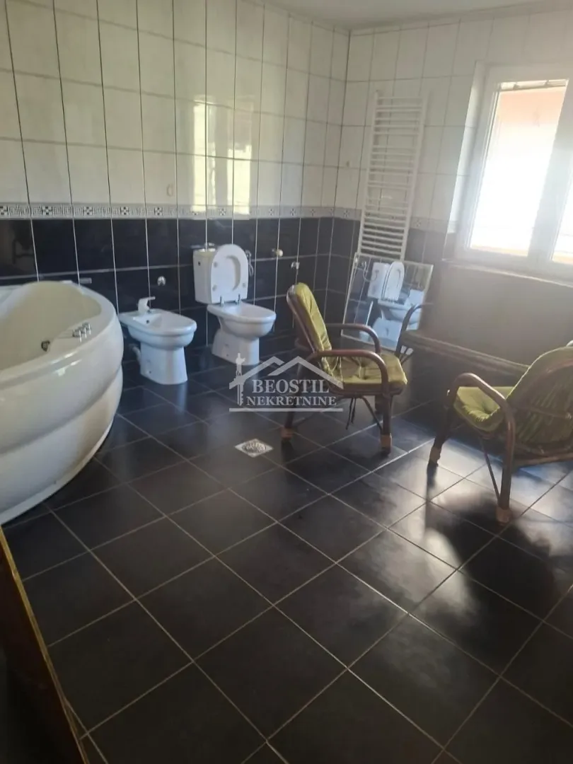 Spacious bathroom with a bathtub, sanitary ware, and armchairs.