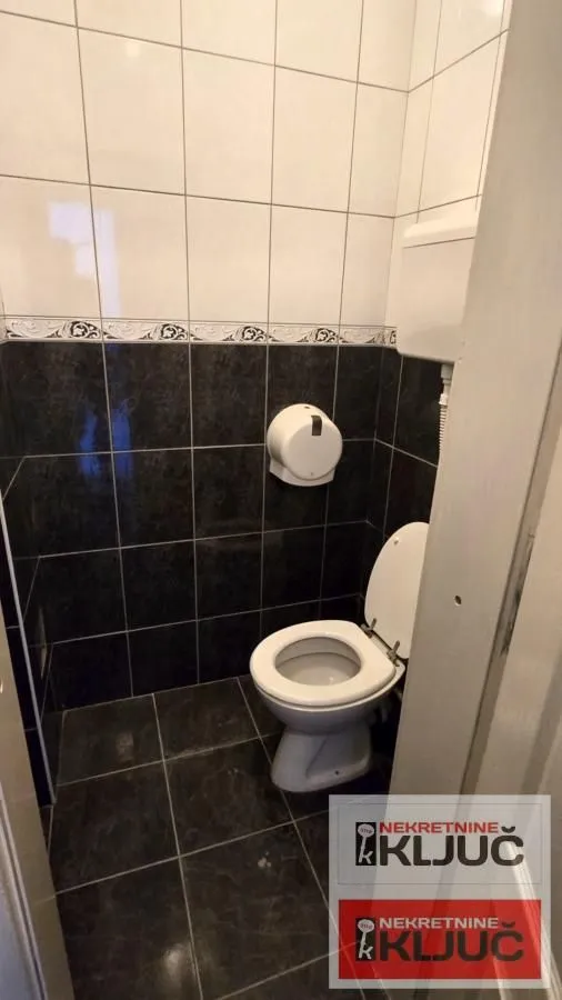 Small bathroom with a toilet and wall tiles.