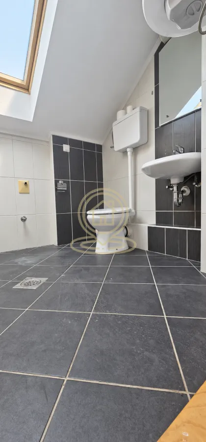 Kupatilo u potkrovlju sa WC šoljom, umivaonikom i krovnim prozorom.