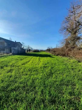 Prostrana zelena parcela sa kućom u pozadini pod vedrim nebom. - image 7