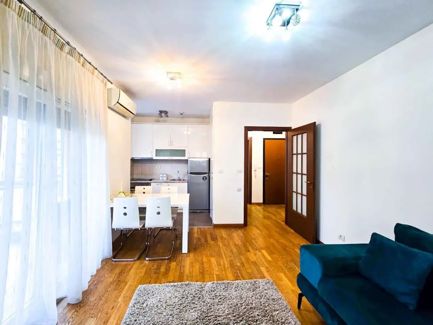 Bright living room with a dining area and kitchen in the background.