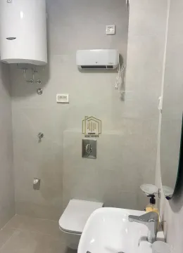 Modern bathroom with neutral-toned tiles, toilet, washbasin, and water heater. - image 6