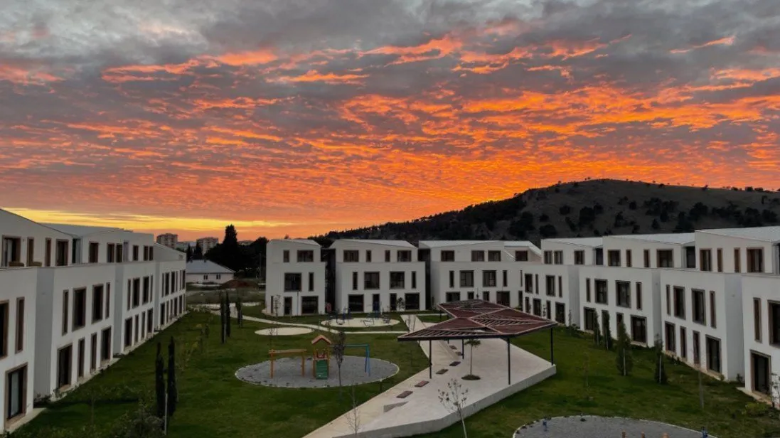 Pogled na eksterijer stambenog kompleksa i dvorište tokom zalaska sunca.
