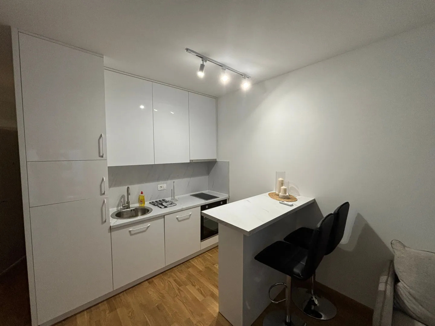 Modern white kitchen with a breakfast bar and black bar stools.