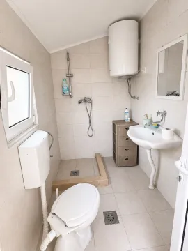 Small bathroom with a walk-in shower area, washbasin, and toilet. - image 19