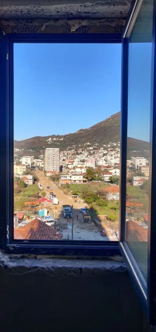 Pogled kroz prozor na okolna brda i naselje.
